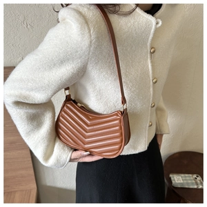 Macro detail of brown V-quilted faux leather shoulder bag with elegant gold hardware