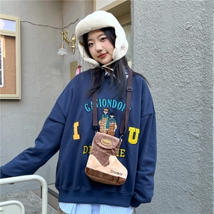 Winter wool crossbody bag in brown boot shape paired with a navy graphic sweatshirt