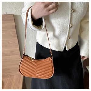 Detail of caramel PU leather shoulder bag with stylish V-shaped quilting and gold zipper
