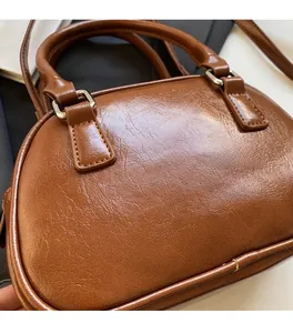 Detail of dark brown leather handbag showing soft wrinkled texture and silver buckle