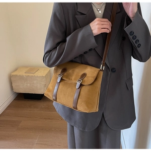 Detailed side view of brown suede messenger bag with leather straps and metal buckles