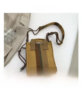 Close-up of khaki canvas tote with vertical stripes and woven rope handle on white background