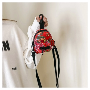 Detail of red floral canvas mini crossbody bag with black adjustable strap and front pocket