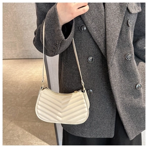 Model wearing a stylish cream PU leather underarm bag with V-shaped quilted texture