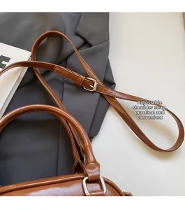Detail view of the adjustable brown PU leather shoulder strap with silver hardware buckle