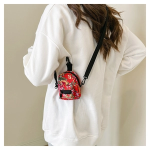 Detail of red floral canvas crossbody bag with traditional peony pattern on model back