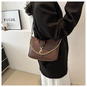 Detail view of dark brown PU leather shoulder bag with gold chain and strap shown on model