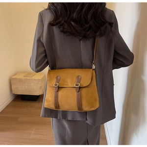 Detail of winter ginger yellow suede shoulder bag with brown leather straps and vintage buckles