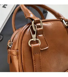 Close-up of polished silver buckle and high-gloss brown leather bag texture