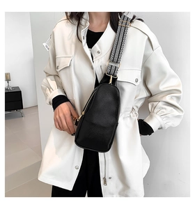 Dettaglio della borsa pettorale in pelle nera con tracolla in tessuto bianco e nero alla moda