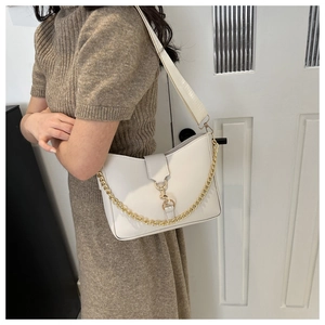 Detail of white PU leather crossbody bag with decorative gold chain and wide strap