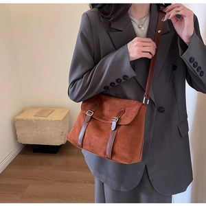 Close-up of caramel suede crossbody bag with vintage brown leather straps and metal buckles