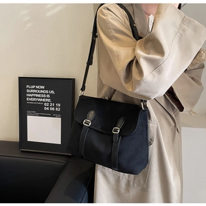 Detail view of stylish black velvet crossbody bag with vintage buckle straps and long shoulder strap
