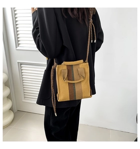 Detail of woven square crossbody bag with ginger yellow stripes and rope shoulder strap