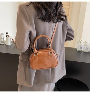 Detail of brown PU leather handbag with silver metallic zipper and sleek dual top handles