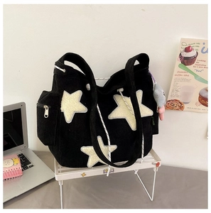Detail van zwarte corduroy tote bag met zijzak met rits en schattige kattenknuffelhanger