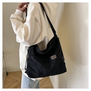 Détail du sac à bandoulière en velours côtelé noir avec étiquette et texture rayée