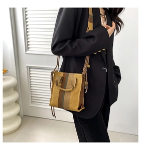 Detailed shot of a vertical striped woven handbag with cross-body strap on a model