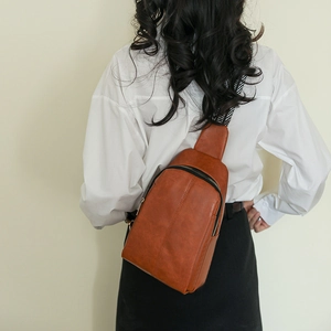 Detail of vintage brown PU leather crossbody bag with geometric woven strap on model