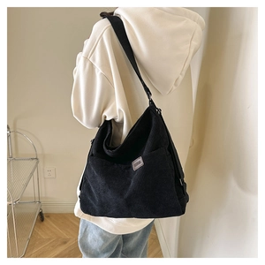 Détail d'un sac à bandoulière en velours côtelé noir avec étiquette sur un mannequin