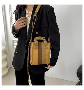 Detail of trendy striped canvas handbag featuring thick rope crossbody shoulder strap