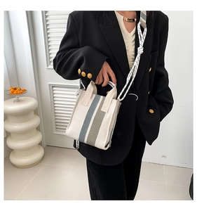 Detail of canvas striped tote bag with braided rope shoulder strap on a model