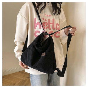 Détail du sac bandoulière en velours côtelé noir avec poche latérale et sangle en nylon