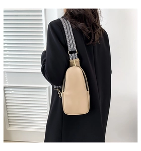 Dettaglio borsa a tracolla beige motivo litchi con ampia tracolla geometrica bianca e nera