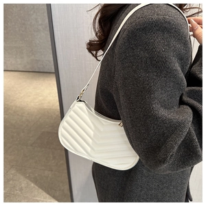 Detail of white quilted leather underarm bag with V-shaped stitching and crescent silhouette