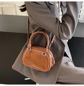 Macro detail of caramel brown leather handbag with silver metallic zipper and sleek finish