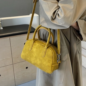 Detail of trendy mustard yellow matte handbag with silver hardware and shoulder strap