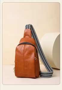 Close-up of caramel leather sling bag featuring lychee texture and striped woven strap