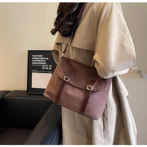 Close-up of brown suede crossbody bag featuring leather straps and golden buckles