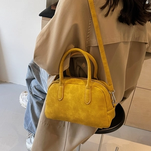 Detail showing the bright yellow suede Boston bag with a stylish long shoulder strap