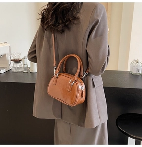 Rear view of model wearing a glossy brown PU leather crossbody bag in a cafe setting