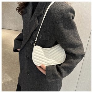 Close-up of a white V-quilted underarm bag worn with a grey herringbone wool blazer
