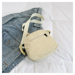 Borsa a tracolla in velluto a coste bianco crema su una giacca di jeans blu in stile casual