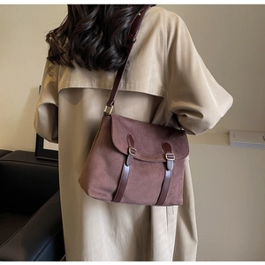 Detail of vintage brown suede crossbody bag with leather straps on a khaki trench coat