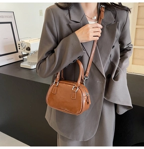 Close-up of brown glossy PU leather handbag worn by model with silver hardware detail