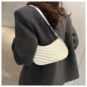 Modern white quilted crescent bag styled with a grey blazer for a fashionable look