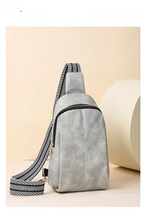 Detail of grey textured cross-body bag with adjustable striped woven strap and zipper