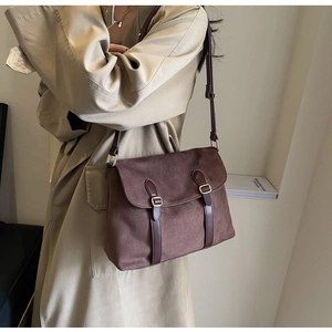 Detail showing the brown suede crossbody bag with vintage gold metal buckle and leather strap