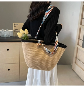 Detail of woven straw tote bag featuring silk scarf handle and wooden bead accents