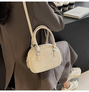 Close-up of cream PU leather Boston bag with adjustable strap and silver metal zipper
