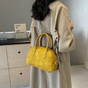 Detail view of yellow suede bowling bag with silver hardware and detachable strap