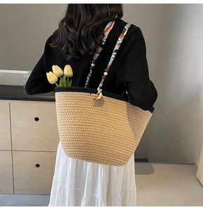 Detail of woven straw tote bag featuring a striped silk scarf strap and wood bead accents