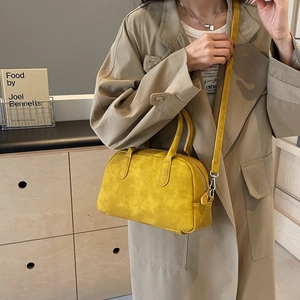 Detail view of mustard yellow Boston style handbag with soft suede texture and silver hardware