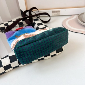 Close-up of multicolor wool fabric crossbody bag with dark green grid textured base