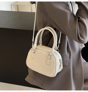 Detail of cream white glossy bowling bag with silver hardware on a shoulder strap