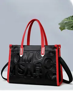 Détail du sac à bandoulière montrant le contraste de l'anse rouge et le gaufrage 3D